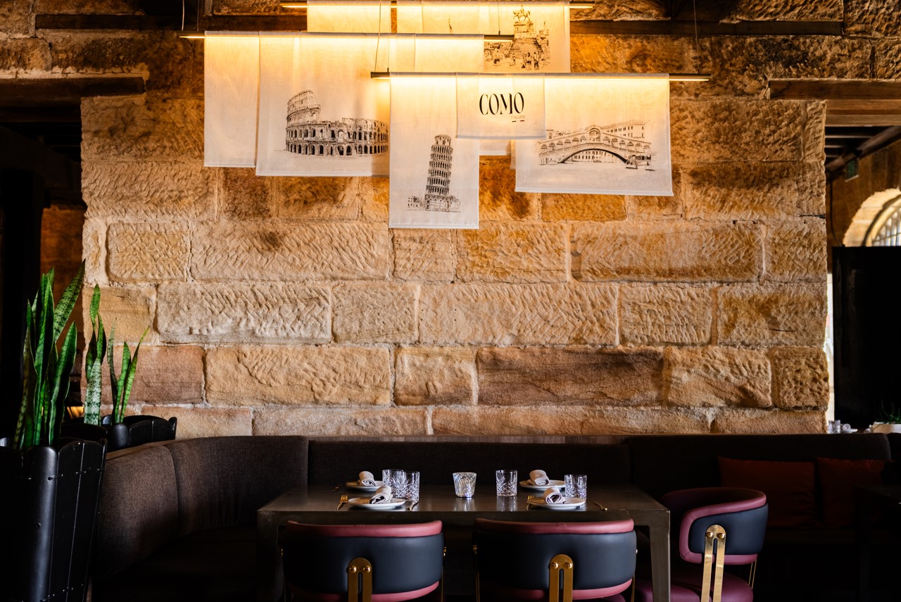 Como sandstone dining room with burgundy seating and Italian wall art